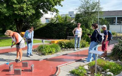 Mitglieder der Frauengemeinschaft Langendorf aus Langendorf (4513, Kanton Solothurn) spielen gemeinsam Minigolf auf einer Anlage im Grünen.