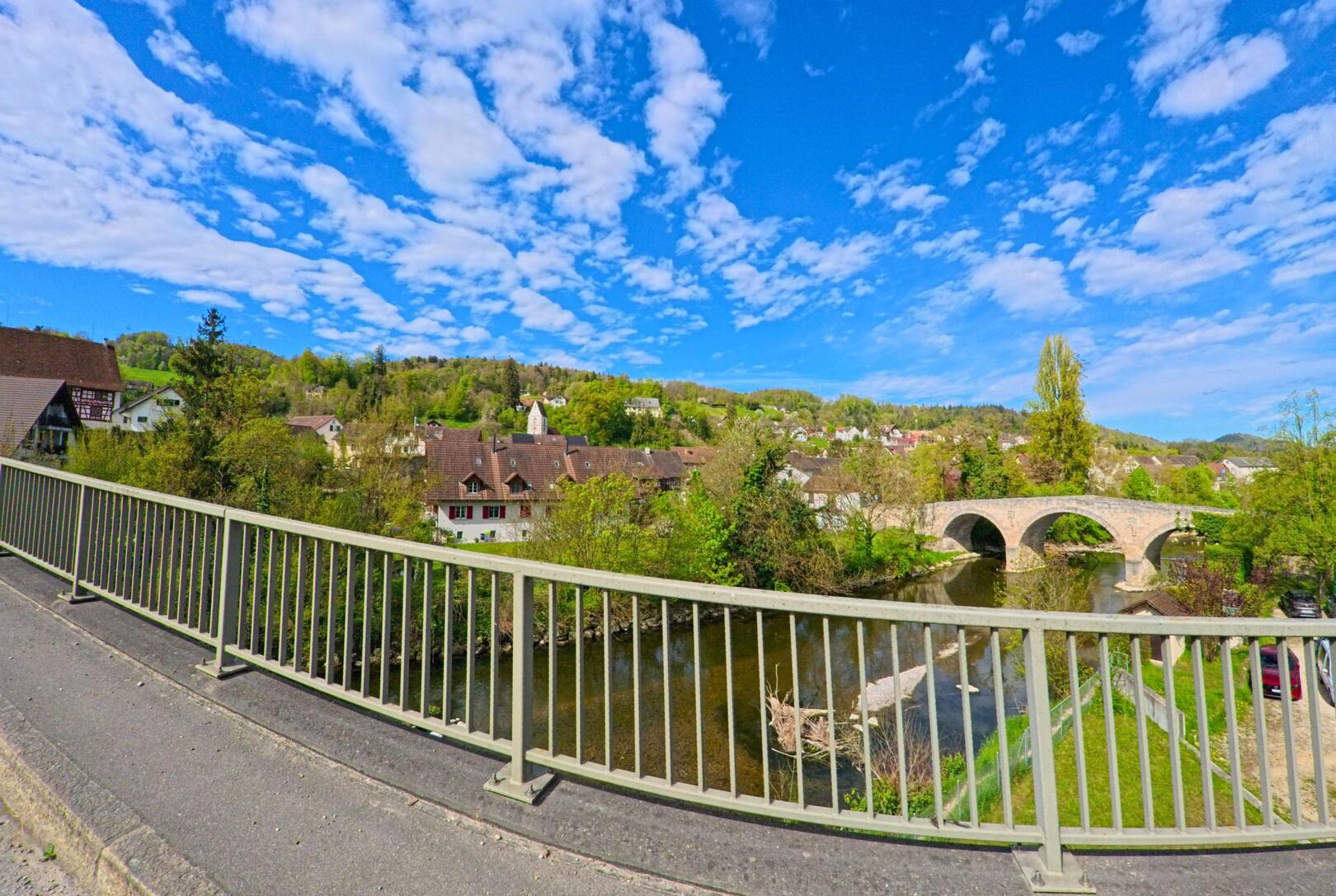 Von einer modernen Brücke aus bietet sich in Freienstein-Teufen (PLZ 8427, Kanton Zürich) ein weiter Blick auf das Dorf und die alte Steinbrücke über die Thur.