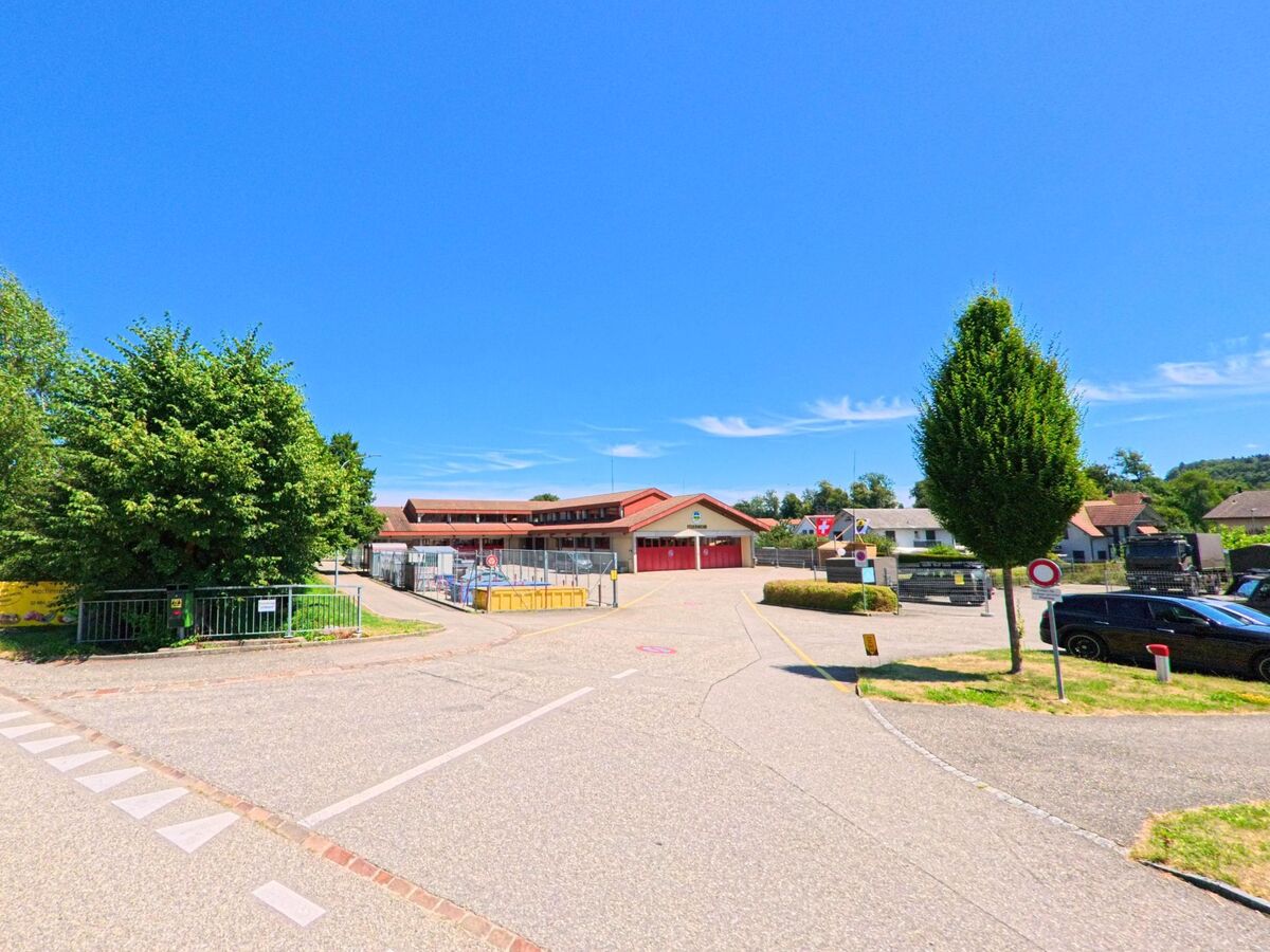 In Fulenbach (4629, Kanton Solothurn) befindet sich das Feuerwehrgebäude mit roten Toren auf einem umzaeunten Areal mit Einfahrt, umgeben von Baeumen und Parkplaetzen.