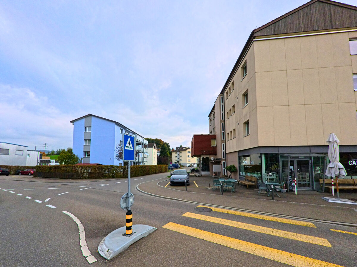 Eine Kreuzung mit Fussgaengerstreifen und Geschaeftsbauten praegt das Strassenbild in Gaiserwald (9032, Kanton St. Gallen).