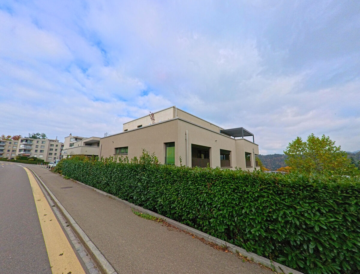 Ein moderner Flachbau mit klaren Linien steht hinter einer Hecke an einer Strasse in Gaiserwald (9032, Kanton St. Gallen).