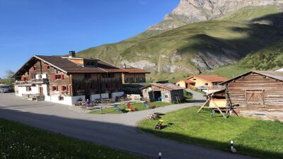 In Thalkirch (7109, Kanton Graubuenden) liegt der Gasslihof mit traditionellen Holzhäusern, roten Fensterlaeden und Blick auf die umliegenden Berge.