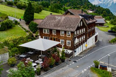 In Gurtnellen (6482, Kanton Uri) steht ein traditionelles Gasthaus mit Holzfassade und Blumenkästen, daneben eine Terrasse mit Sonnenschirm und Sitzplätzen.