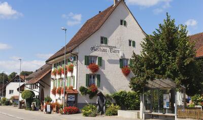 In Boezen (5076, Kanton Aargau) steht ein traditionelles Gasthaus mit roten Blumenkasten an den Fenstern direkt an der Hauptstrasse.