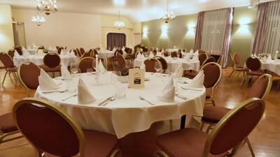 Im Gasthof Roessli in Ruswil (6017, Kanton Luzern) sind die festlich gedeckten Tische im grossen Saal für ein Abendessen vorbereitet, mit Kerzenlicht und eleganter Dekoration.