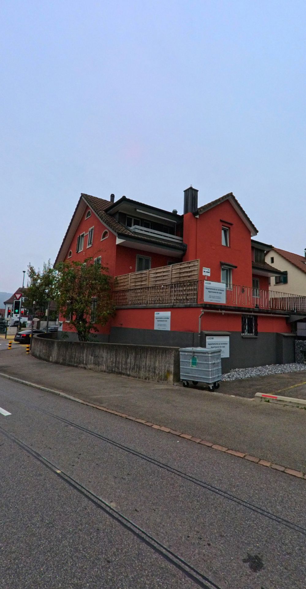 Ein rot gestrichenes Mehrfamilienhaus mit Balkon und Geschäftsräumen im Erdgeschoss steht an einer Strasse in Gebenstorf (5412, Kanton Aargau).