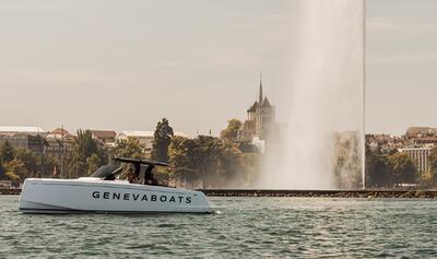 Ein Boot von Genevaboats fährt in Genève (1211, Kanton Genf) über den See, im Hintergrund sind der Jet d’Eau und die Altstadt zu sehen.