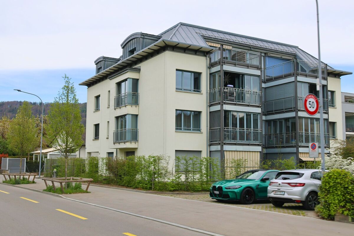 Ein modernes Mehrfamilienhaus mit grosszügigen Balkonen steht in Geroldswil im Kanton Zürich, PLZ 8954, an einer verkehrsberuhigten Strasse mit Tempo-50-Zone.