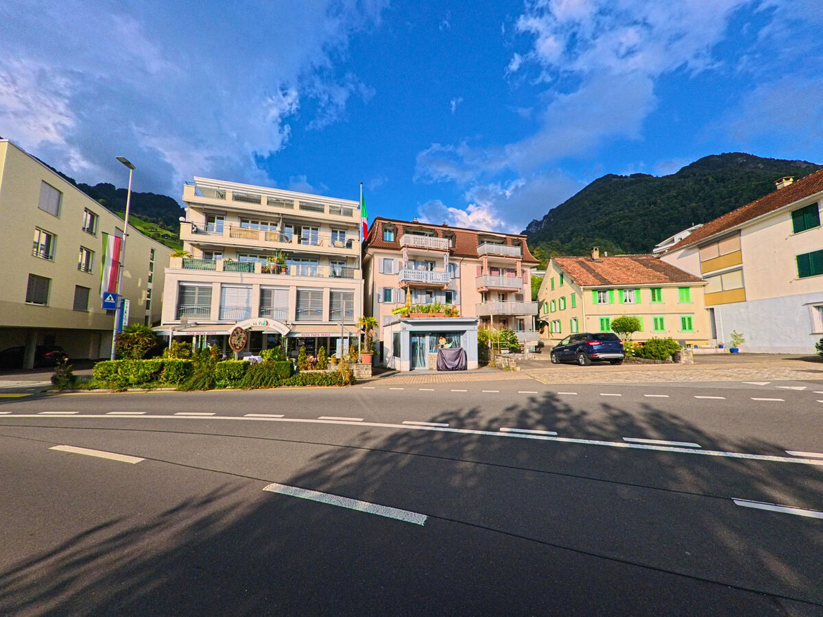 Vor Wohnhäusern mit Balkonen öffnet sich ein Platz an der Strasse in Gersau (6442, Kanton Schwyz).