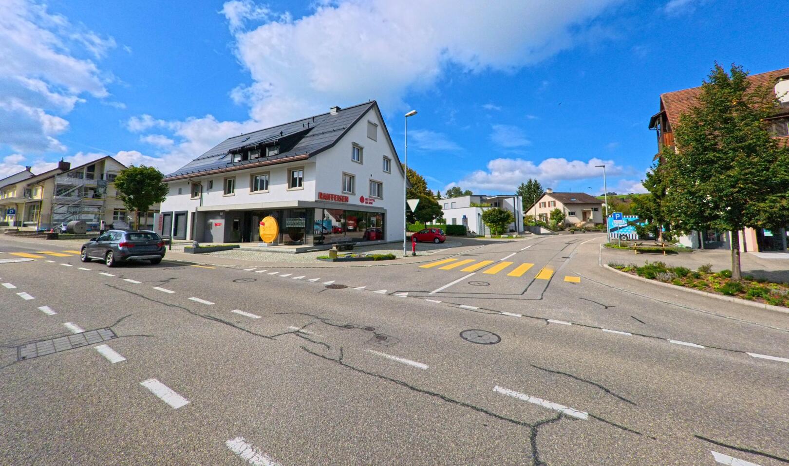 An der Hauptstrasse in Gipf-Oberfrick (5073, Kanton Aargau) steht das Gebäude der Raiffeisenbank, umgeben von Wohnhäusern und einer gut ausgebauten Kreuzung mit Fussgängerstreifen.