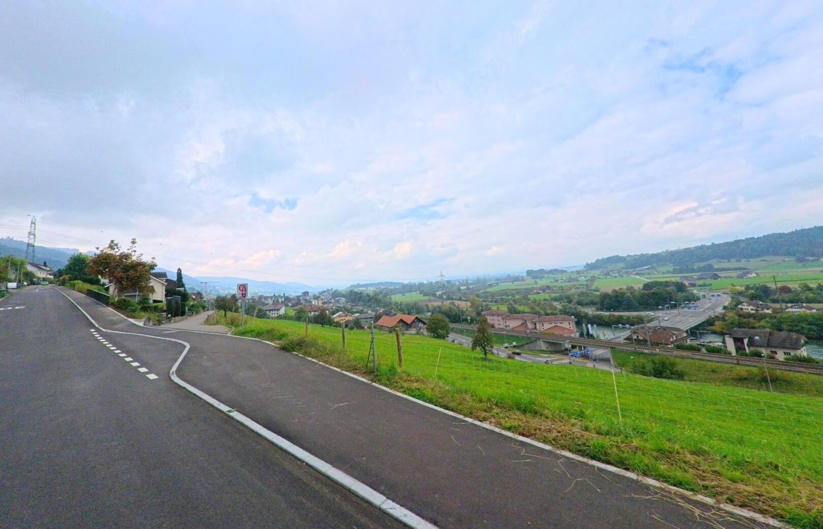 Von einer ansteigenden Strasse in Gisikon (6038, Kanton Luzern) bietet sich ein weiter Blick ueber das Reusstal und die umliegende Landschaft.