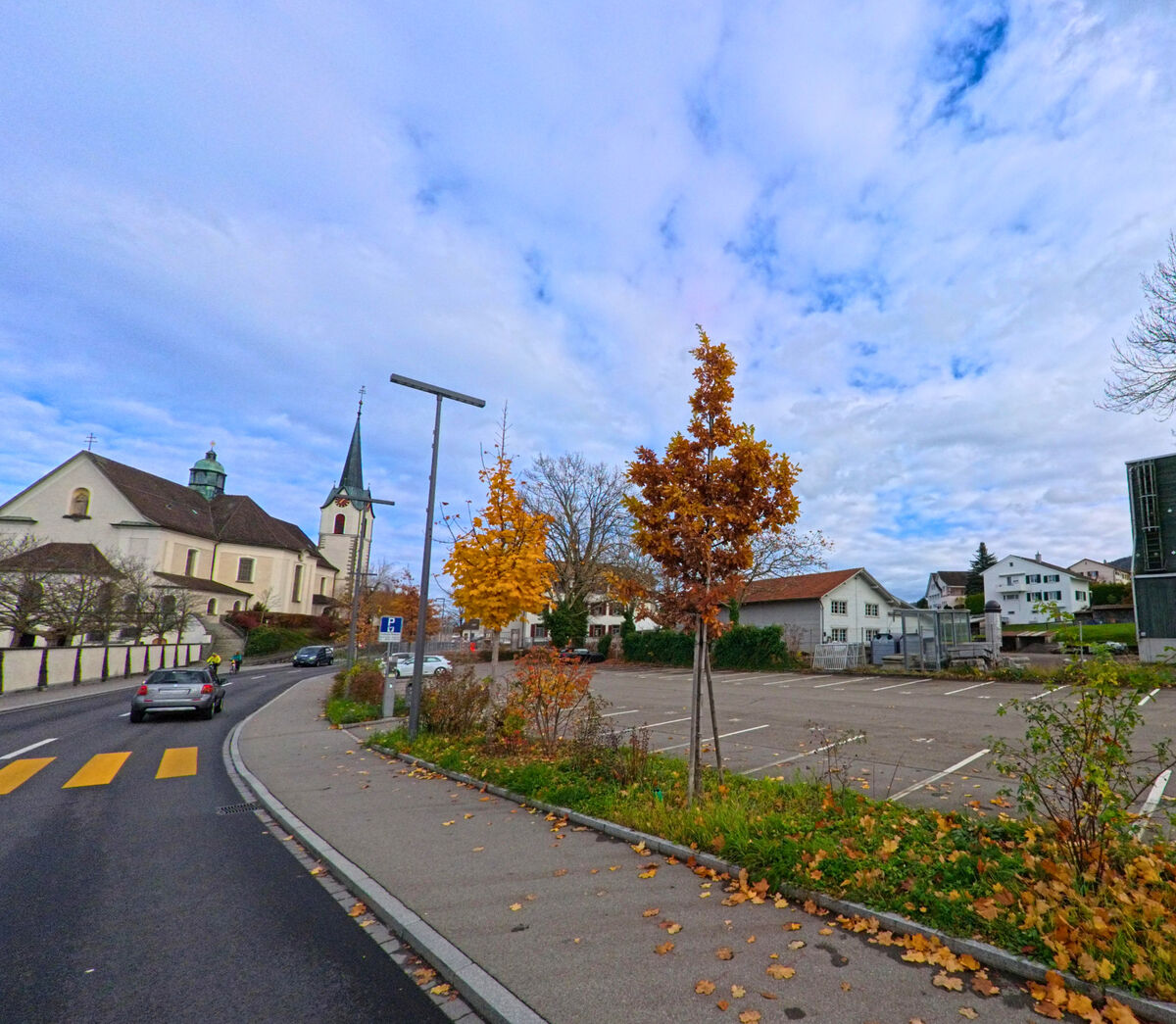 Eine Strasse fuehrt in Richtung Kirche durch ein Wohngebiet von Goldach (9403, Kanton St. Gallen) im Herbst.