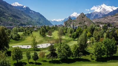 Der Golf Club de Sion in Sion (1950, Kanton Wallis) liegt eingebettet in eine grüne Landschaft mit Blick auf die schneebedeckten Alpen und die Burgruine Tourbillon.