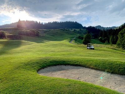 Der Golf Club Villars in Villars-sur-Ollon (1884, Kanton Waadt) liegt inmitten grüner Hügel und Wälder mit einem Golfwagen auf dem Platz.