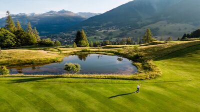 In Klosters (7250, Kanton Graubuenden) liegt der Golfplatz Golf Klosters inmitten gruener Wiesen mit Teich und Blick auf die umliegenden Berge.