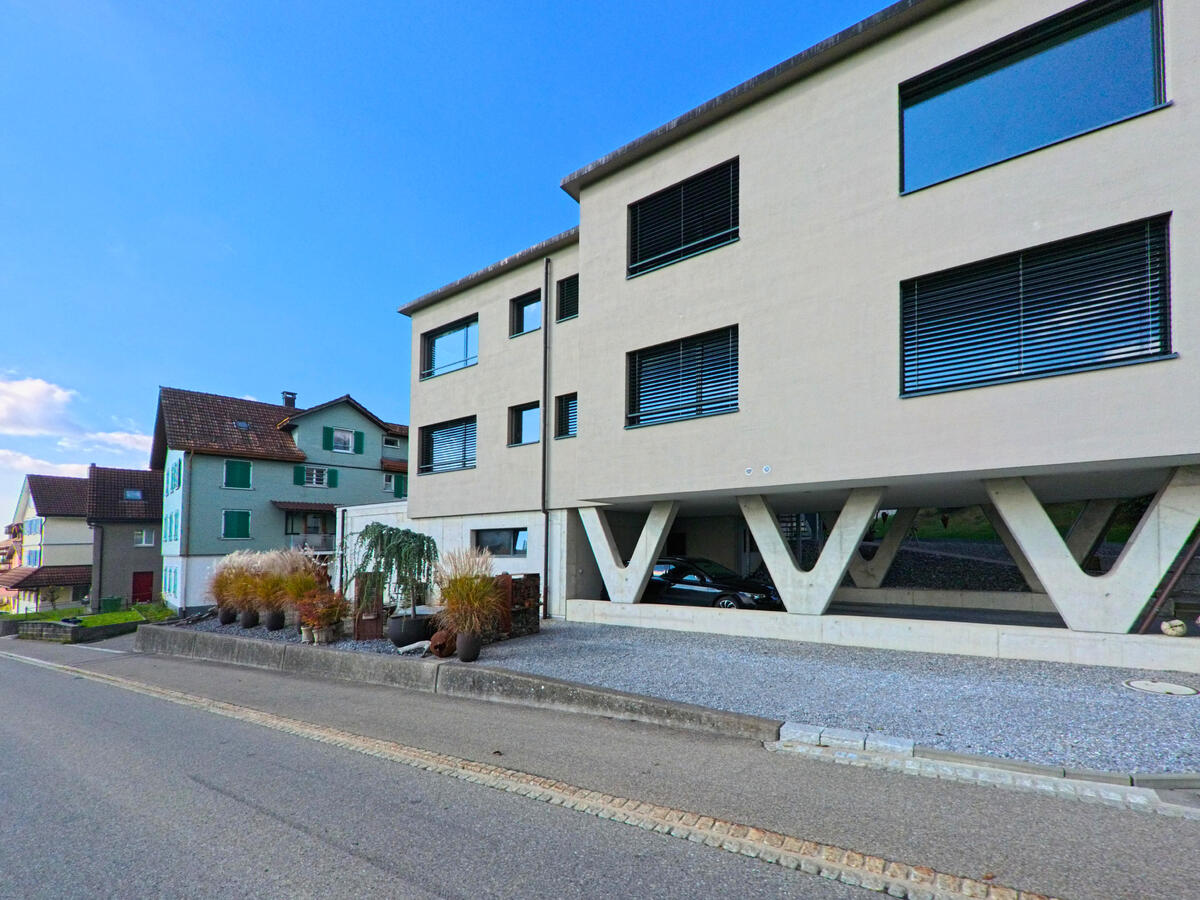 Ein modernes Wohngebaeude mit klarer Fassadengestaltung steht an einer Nebenstrasse in Gommiswald (8737, Kanton St. Gallen).