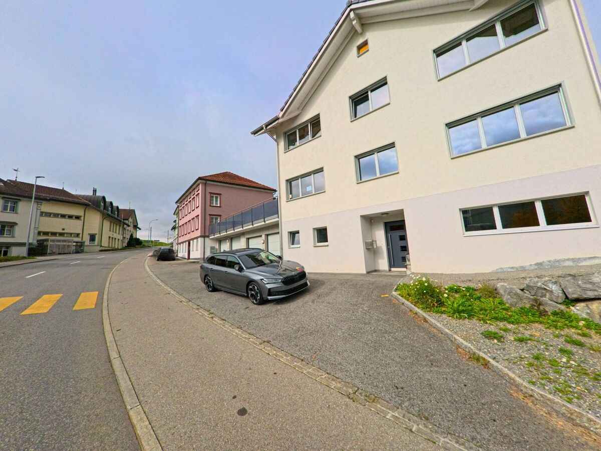 An einer leicht gebogenen Strasse steht ein modernes Wohngebäude in Gonten (9108, Kanton Appenzell Innerrhoden) mit klarer Fassadengestaltung.
