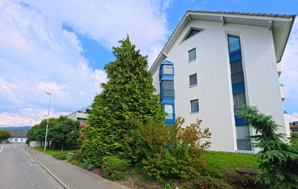 Vor einem mehrgeschossigen Wohnhaus wachsen Bäume und Straeucher in Gonten (9108, Kanton Appenzell Innerrhoden).