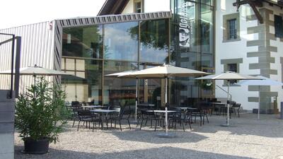 In Luetzelflueh (3432, Kanton Bern) befindet sich das Gotthelf Zentrum Emmental mit moderner Glasfassade und einer sonnigen Terrasse mit Sonnenschirmen.