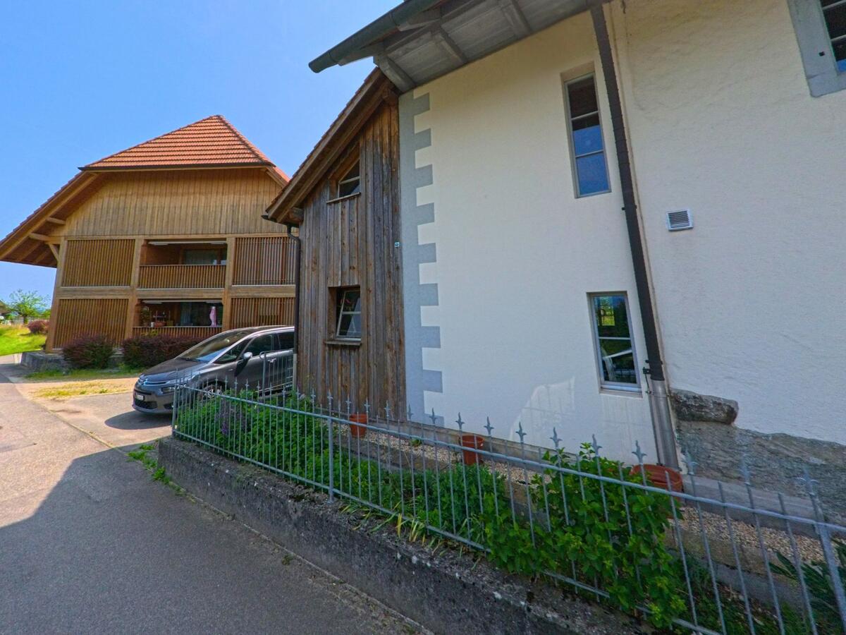 In Graben (3376, Kanton Bern) stehen zwei Wohnhäuser mit traditioneller Holzverschalung und modernen Elementen entlang einer schmalen Strasse.