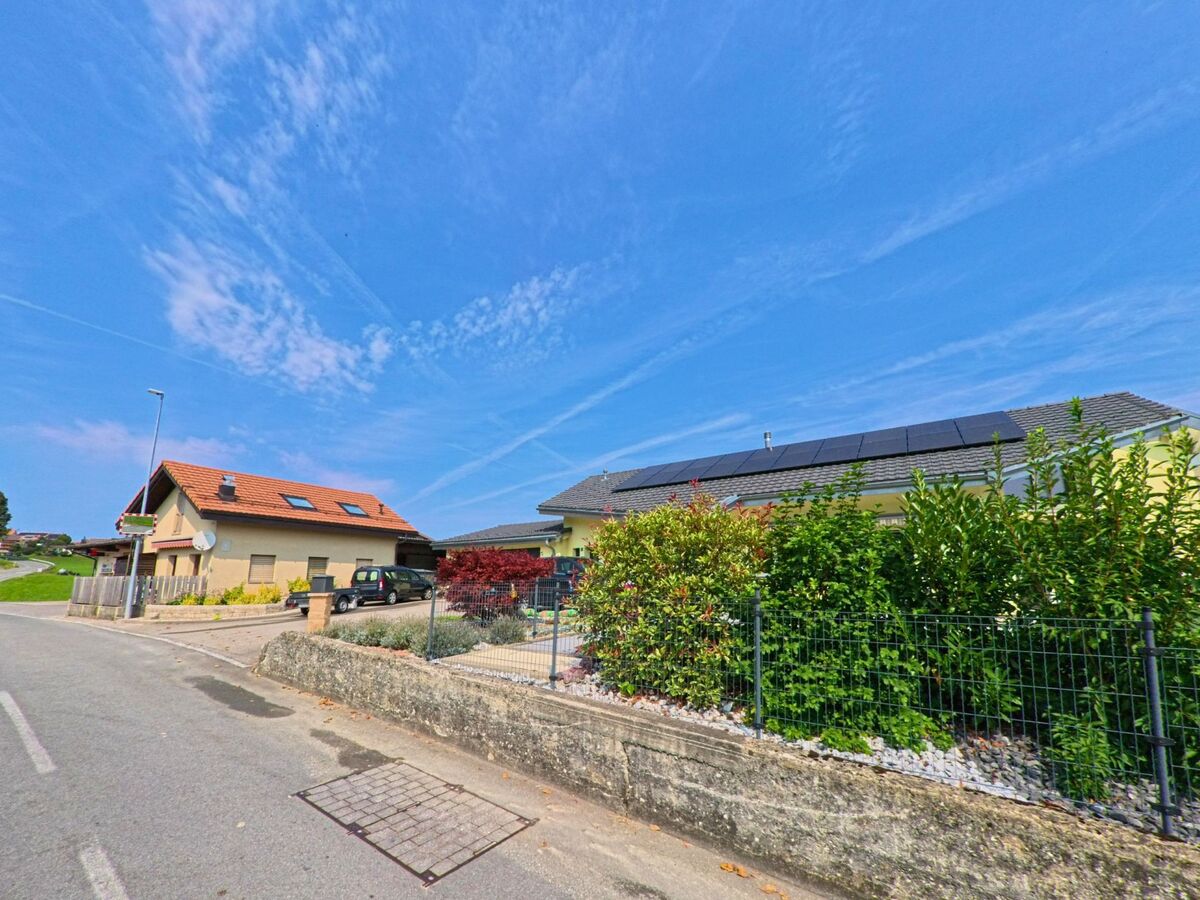 Ein Einfamilienhaus mit roten Dachziegeln und ein Nachbarhaus mit Solarpanelen praegen in Granges_(Veveyse) (1614, Kanton Freiburg) das Strassenbild.