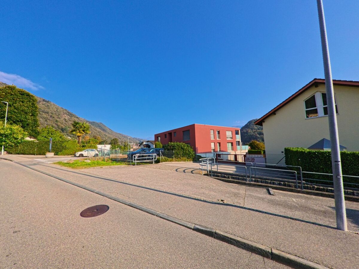 Zwischen Wohnbauten und offenen Flaechen zeigt sich eine ruhige Wohnlage in Gravesano (6929, Kanton Tessin) mit Blick auf die umliegenden Huegel.