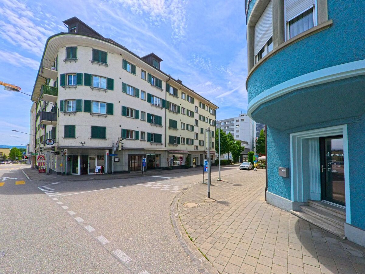 An einer Strassenecke in Grenchen (2540, Kanton Solothurn) stehen mehrstöckige Wohn- und Geschäftshäuser mit farbigen Fassaden und markanten Balkonen.