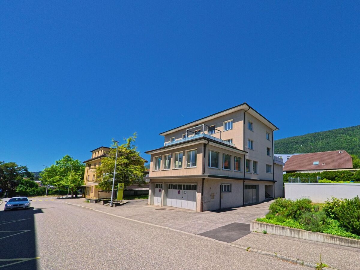 In Grenchen (2540, Kanton Solothurn) steht ein helles Mehrfamilienhaus mit grossen Fenstern und Garageneinfahrten an einer ruhigen Seitenstrasse am Jurasüdfuss.