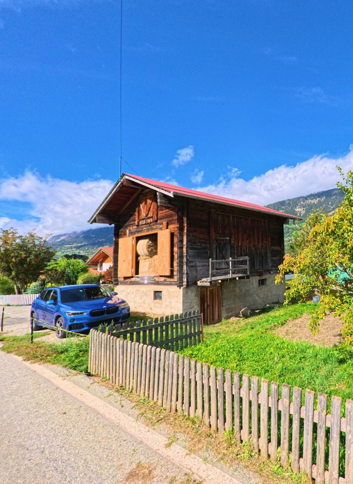 Ein traditionelles Wohnhaus in Grengiols (3993, Kanton Wallis) steht am Rand einer Wiese mit Blick auf die umliegenden Hänge.