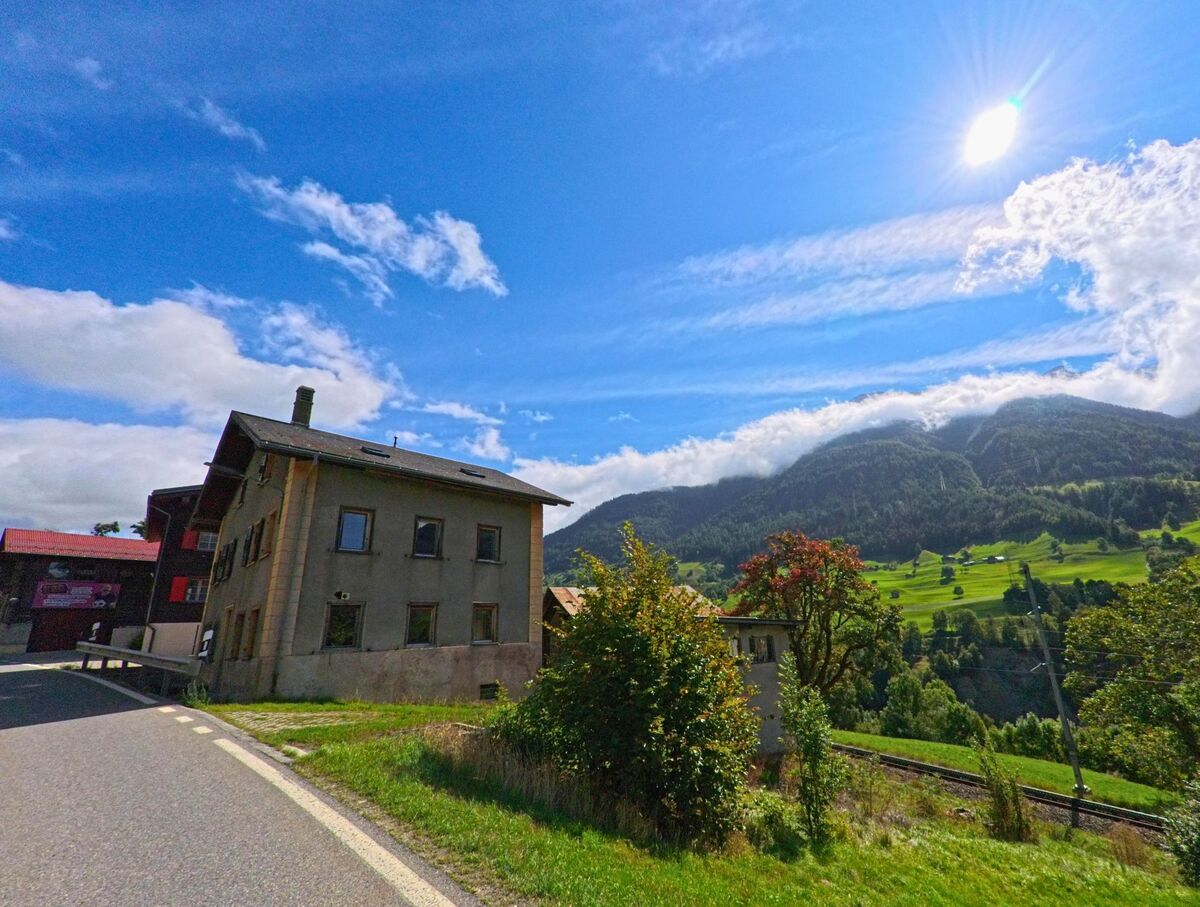 Ein traditionelles Wohnhaus in Grengiols (3993, Kanton Wallis) steht am Rand einer Wiese mit Blick auf die umliegenden Hänge.