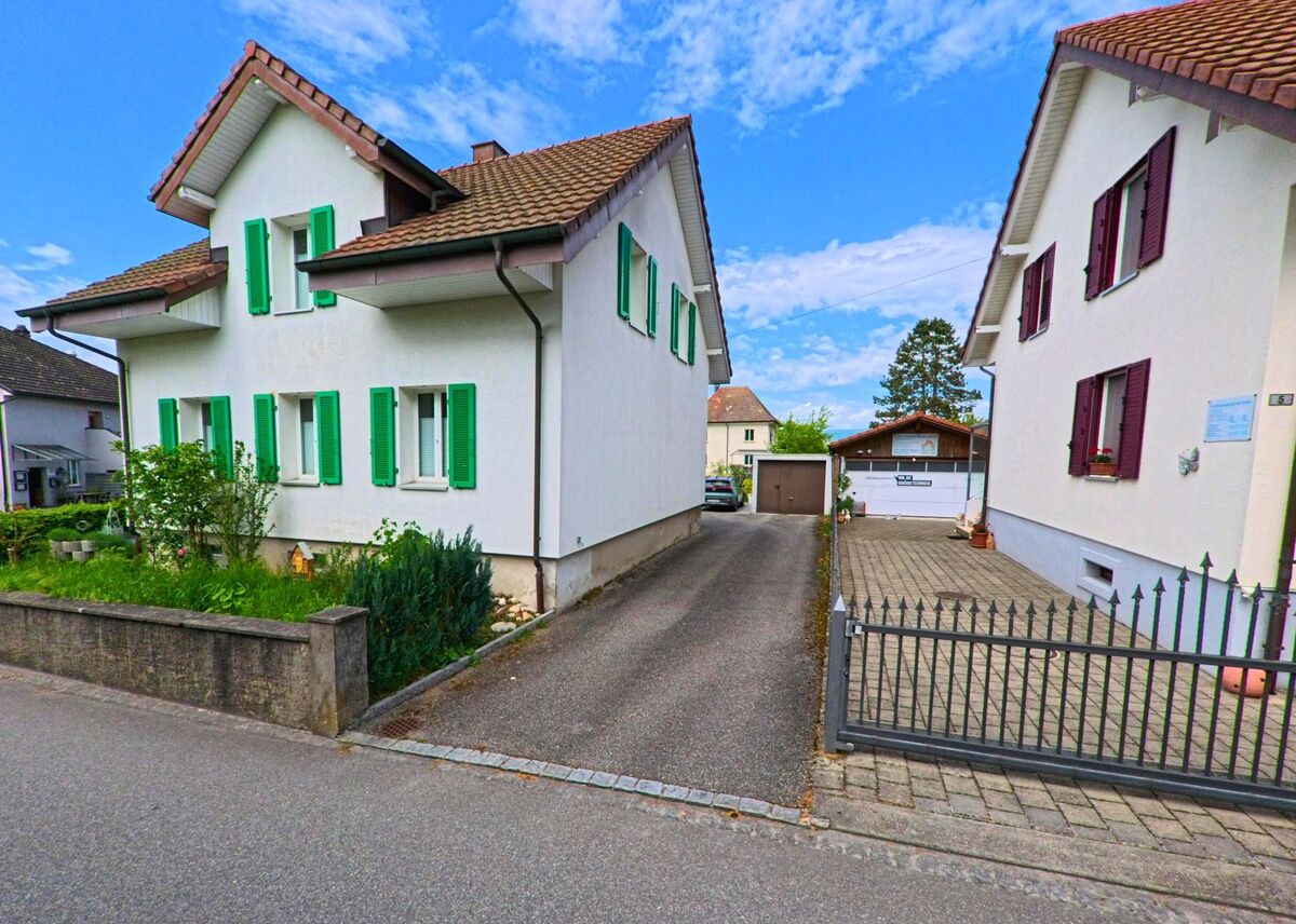 Zwei Einfamilienhäuser mit farbigen Fensterläden stehen in Gretzenbach (5014, Kanton Solothurn) entlang einer schmalen Einfahrt mit Zugang zu Garagen und Höfen.