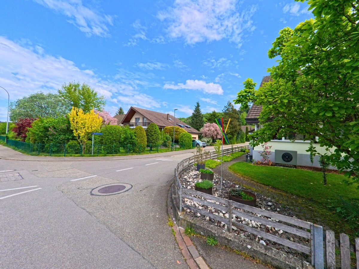 An einer ruhigen Kreuzung in Gretzenbach (5014, Kanton Solothurn) säumen gepflegte Gärten mit blühenden Bäumen und Zäunen die Wohnhäuser.