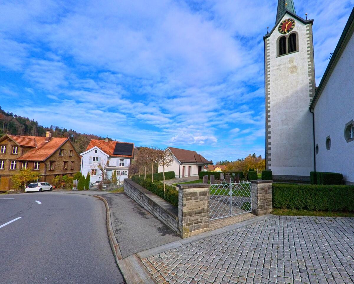 Die Kirche mit Friedhofsmauer befindet sich an einer gebogenen Strasse in Grub (9035, Kanton Appenzell Ausserrhoden).