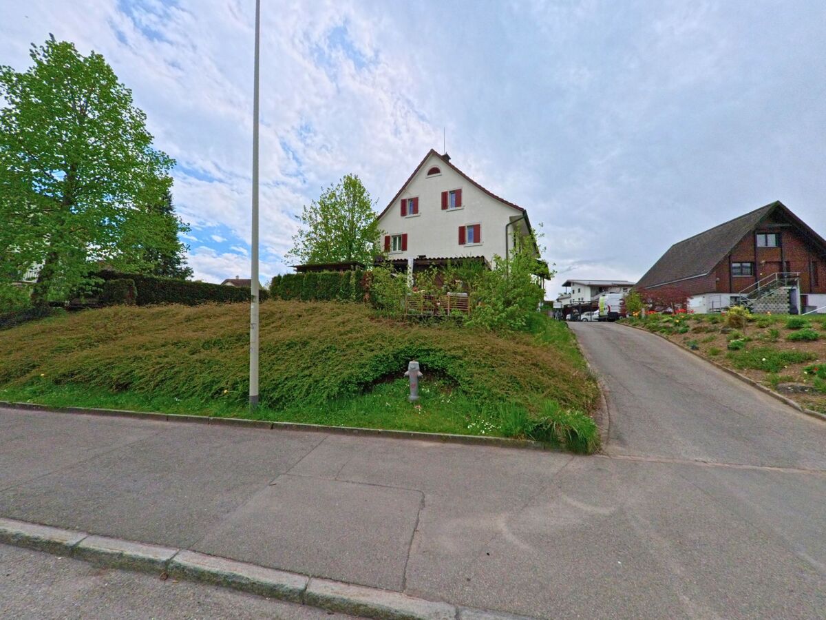 In Grüningen, PLZ 8627 im KANTON Zürich erhebt sich ein Einfamilienhaus mit gepflegtem Garten auf einer leichten Anhöhe neben einem kleinen Privatweg.