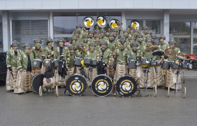 Mitglieder der Guggamusig Lavaria stehen in Lüchingen (9450) im Kanton St. Gallen in Kostuemen mit Trommeln vor einem Gebaeude.