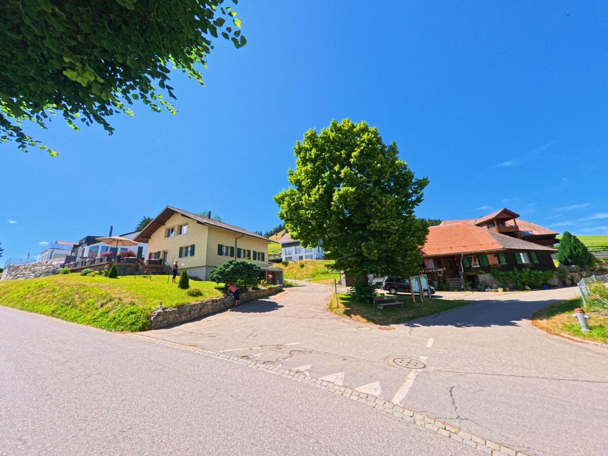 Am sonnigen Hang in Guggisberg (3156, Kanton Bern) stehen Einfamilienhäuser mit gepflegten Vorgärten und Blick auf die umgebende Landschaft.