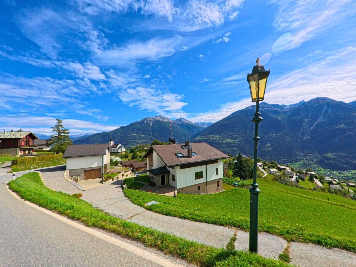 Am Hang von Guttet-Feschel (3956, Kanton Wallis) stehen Einfamilienhäuser mit Blick auf das Tal und die hohen Berge im Hintergrund.