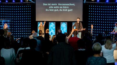 In Seegräben (8607, Kanton Zürich) begleitet eine Musikgruppe auf einer beleuchteten Bühne einen Gottesdienst vor stehendem Publikum.