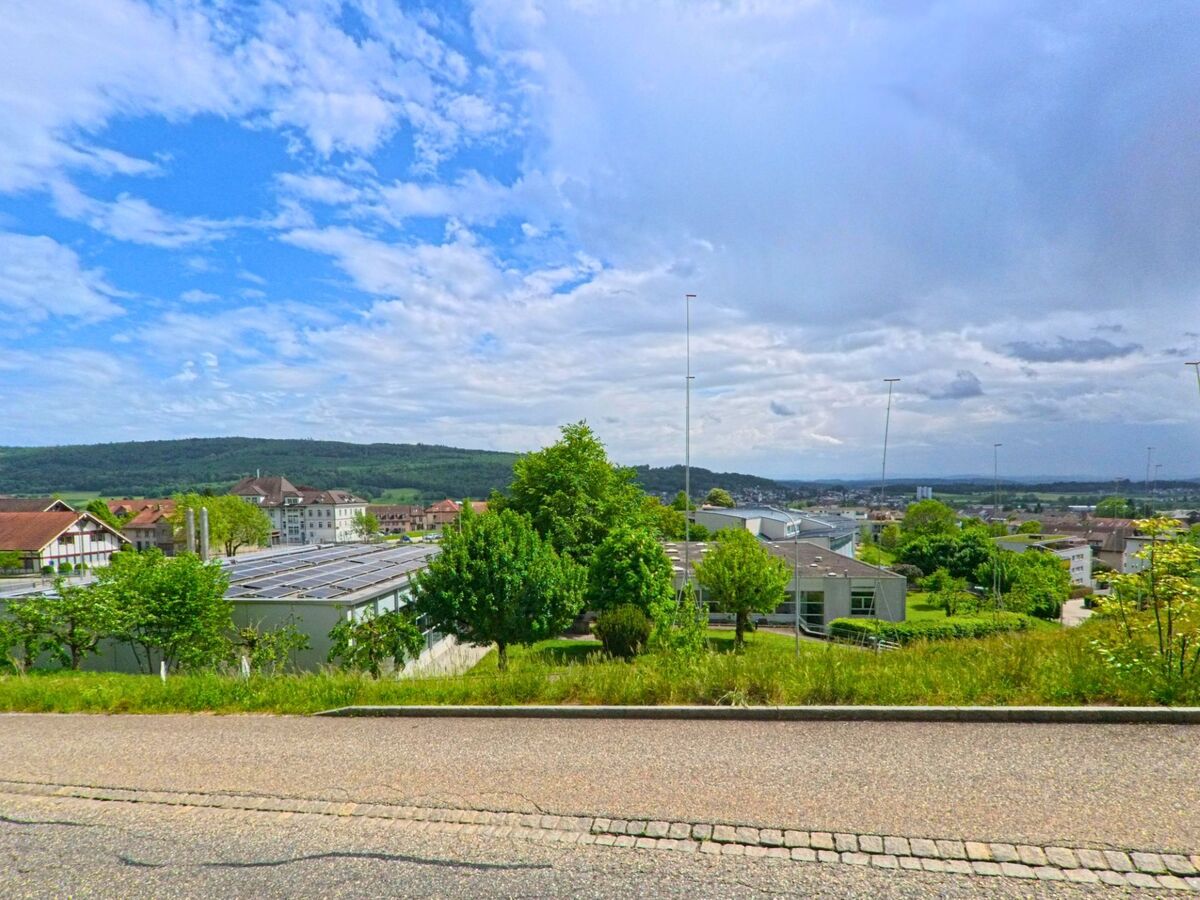 In Hägendorf (4614, Kanton Solothurn) bietet eine leicht abfallende Strasse einen weiten Blick auf das Dorf, die Kirche mit gruenem Turm und das darunterliegende Tal.