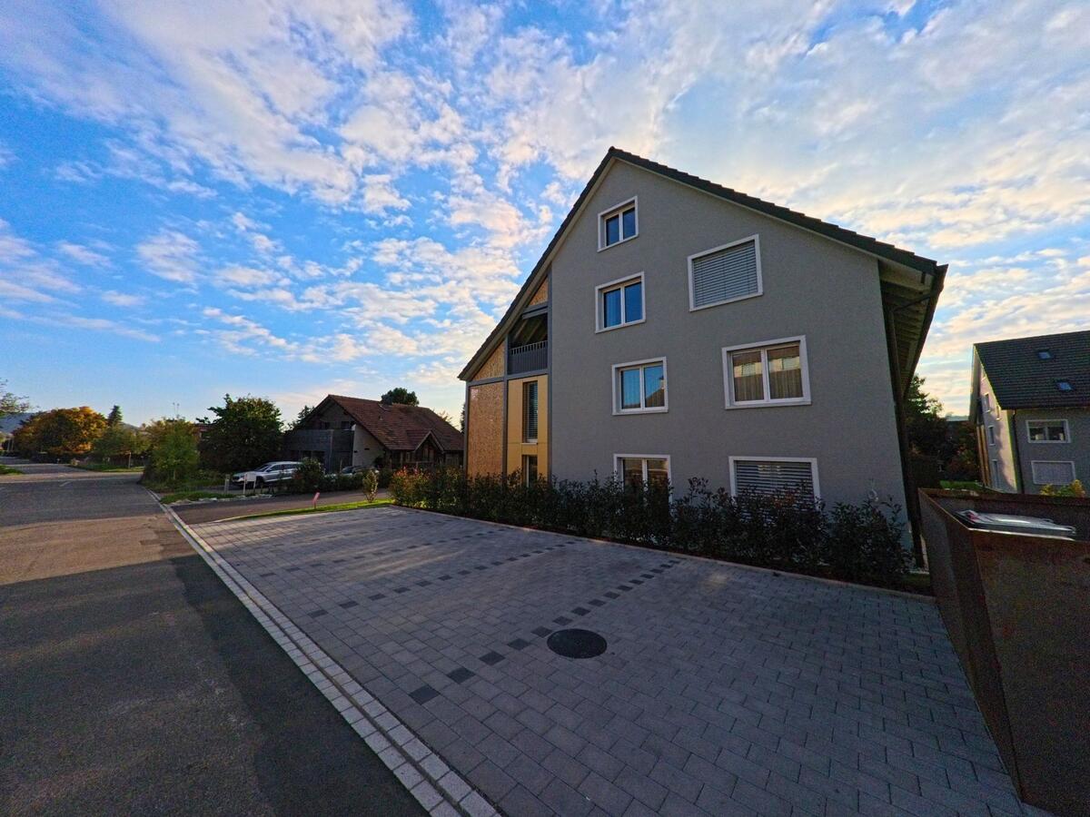 Ein modernes Mehrfamilienhaus grenzt an einen gepflasterten Vorplatz in Hallau (8215, Kanton Schaffhausen).