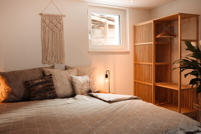 Im Haus Meierhuesli in Malans (7208, Kanton Graubuenden) zeigt ein behaglich eingerichtetes Schlafzimmer mit Holzelementen und warmem Licht eine gemuetliche Atmosphaere.