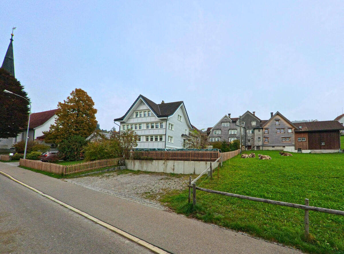 Mehrere Dorfhaeuser stehen entlang einer leicht geschwungenen Strasse in Hemberg (9105, Kanton St. Gallen).