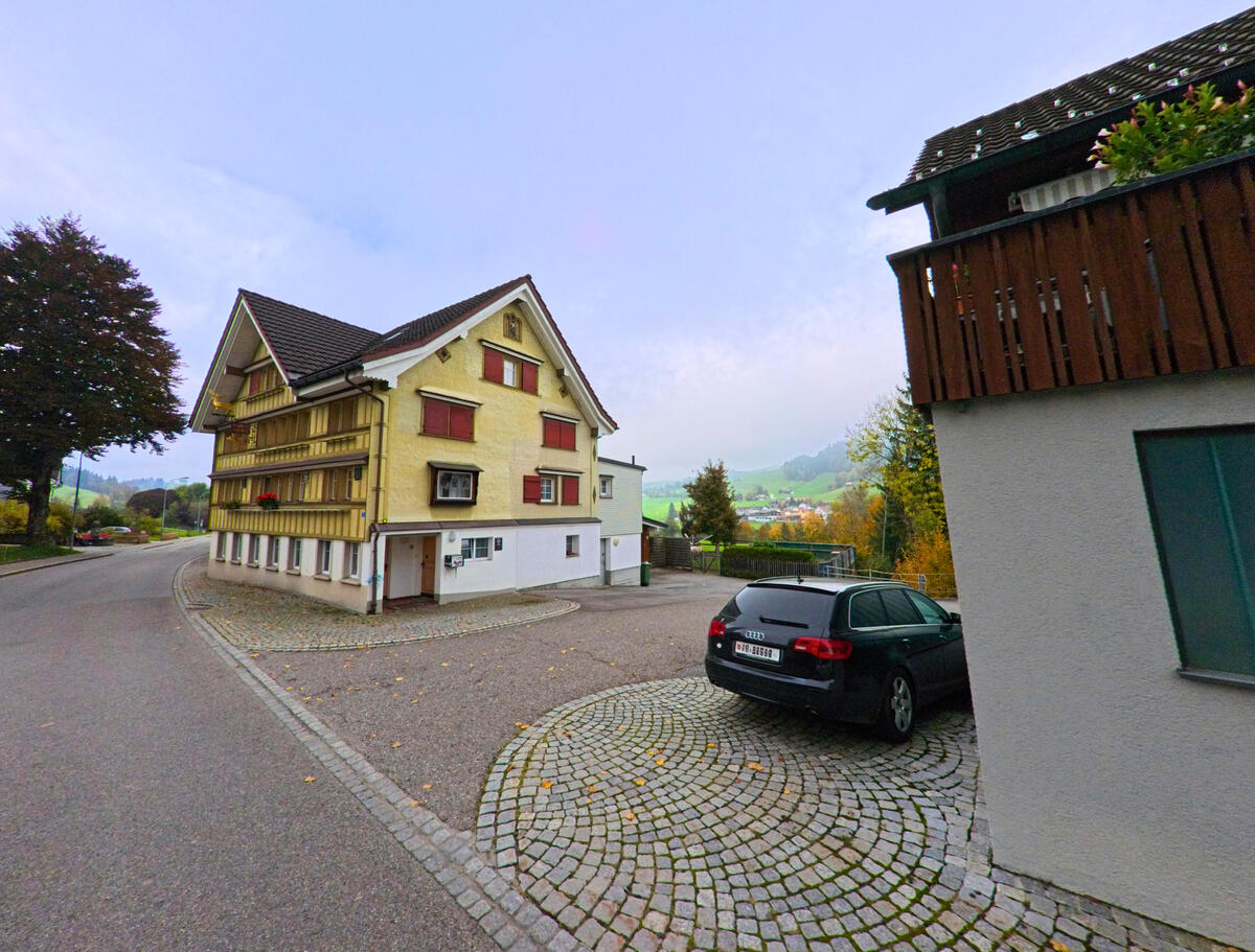 Ein gelb gestrichenes Wohnhaus mit traditioneller Architektur liegt an einer gepflasterten Zufahrt in Hemberg (9105, Kanton St. Gallen).