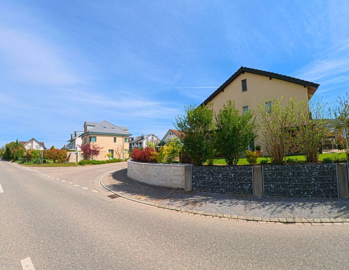 Moderne Einfamilienhäuser mit gepflegten Gärten und Gabionenmauern prägen in Henggart, PLZ 8444 im Kanton Zürich, das Erscheinungsbild eines ruhigen Wohnquartiers.