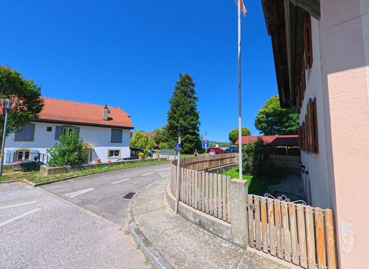 In einer ruhigen Seitenstrasse von Henniez (1525, Kanton Waadt) stehen Wohnhaeuser mit roten Ziegeldächern und kleinen umzäunten Gaerten.