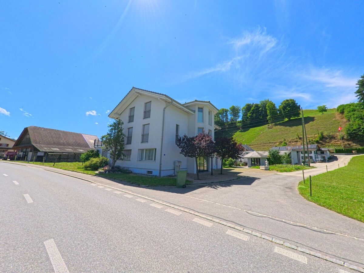 In Hergiswil bei Willisau (6133, Kanton Luzern) stehen ein modernes Wohnhaus und ein traditioneller Hof am Fusse eines bewaldeten Hangs mit gepflegten Wiesen.