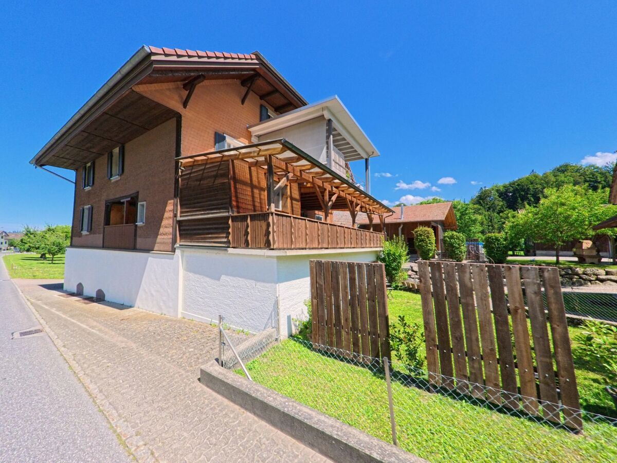 In Hergiswil bei Willisau (6133, Kanton Luzern) steht ein traditionelles Wohnhaus mit überdachtem Holzbalkon und gepflegtem Garten in ruhiger Umgebung.