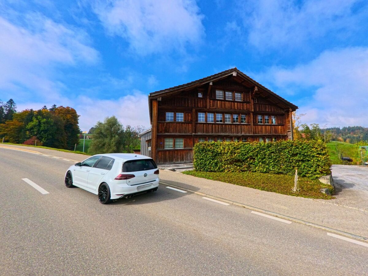 Ein traditionelles Holzhaus liegt an einer leicht geschwungenen Strasse im Quartier von Herisau (9100, Kanton Appenzell Ausserrhoden).