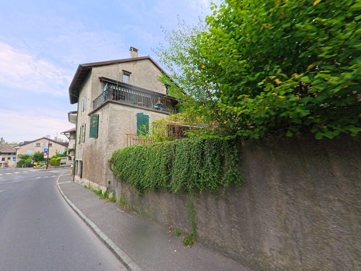 In Hermance (1248, Kanton Genf) führt eine Strasse an einem alten Haus mit grünen Fensterläden und einem Balkon vorbei.