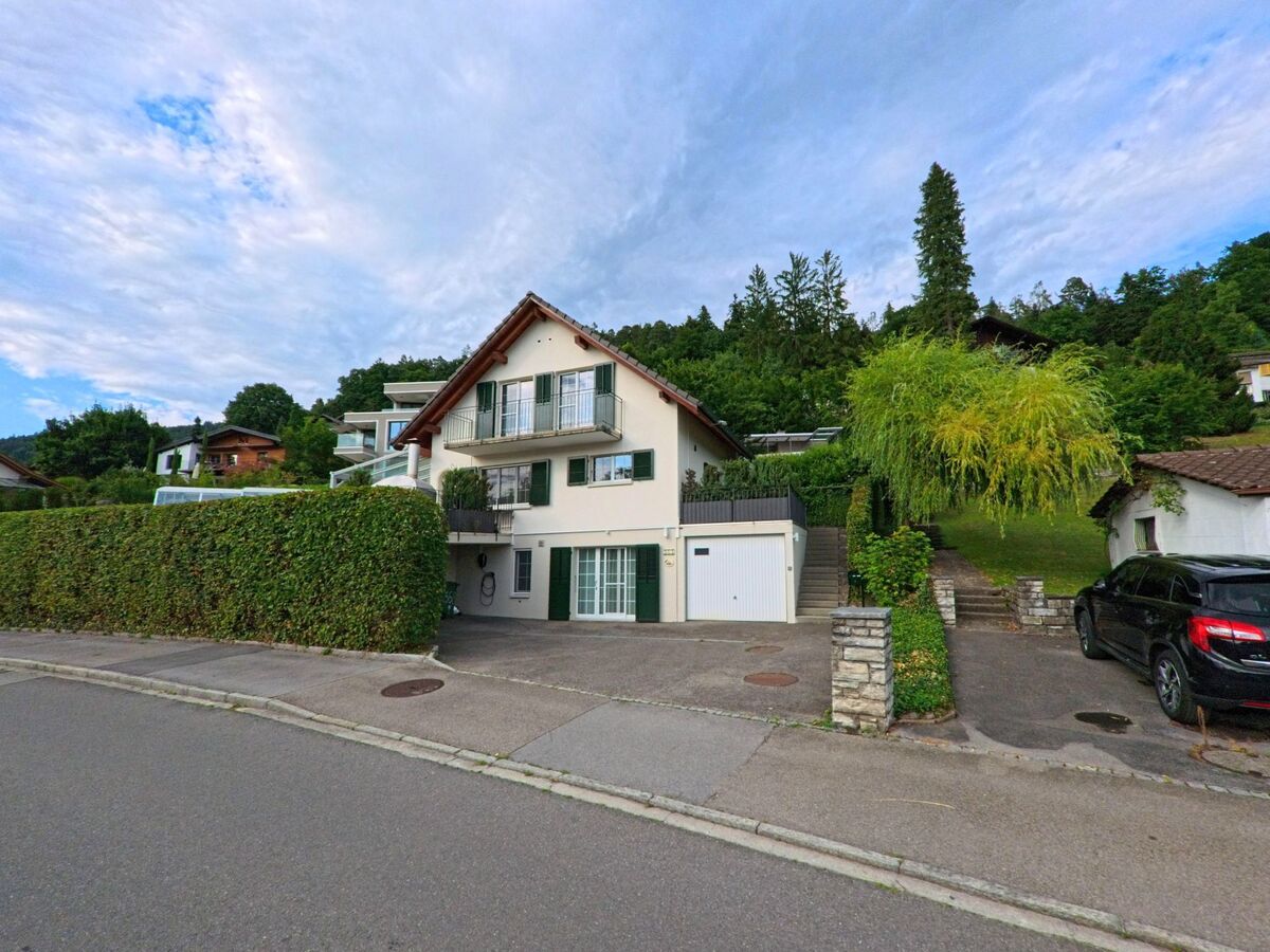 In Hilterfingen (3626, Kanton Bern) führen Treppen und Einfahrten zu terrassenförmig angelegten Einfamilienhäusern mit gepflegten Vorgärten am Hang.